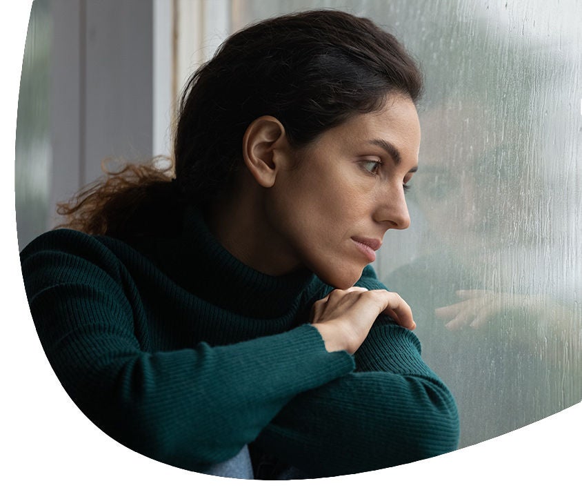Woman looking the rain on her window