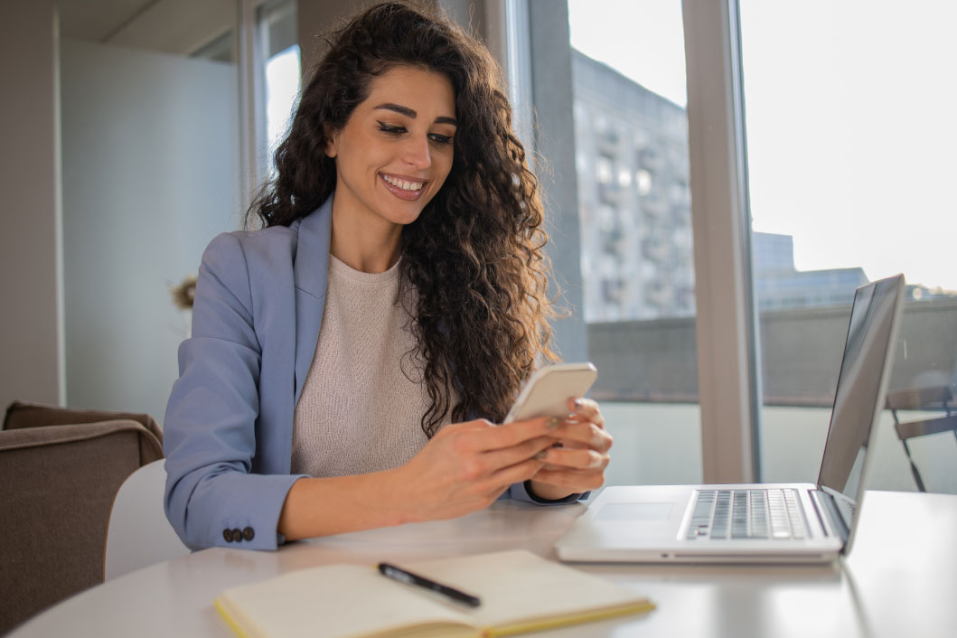 Girl on a table smiling with the phone on hands